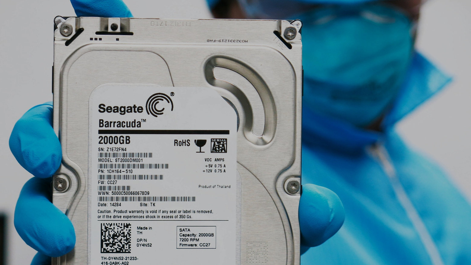 +DR Data Recovery technician holding a Seagate Barracuda hard drive in the cleanroom